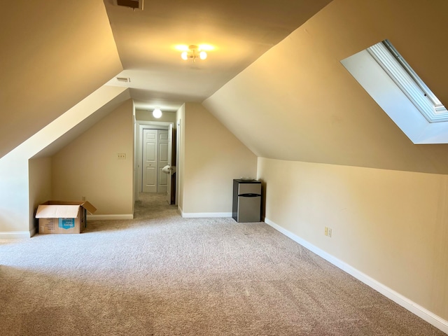 bonus room featuring vaulted ceiling with skylight and light carpet