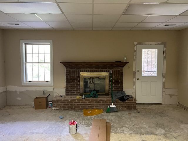 unfurnished living room with a drop ceiling, a fireplace, and concrete flooring