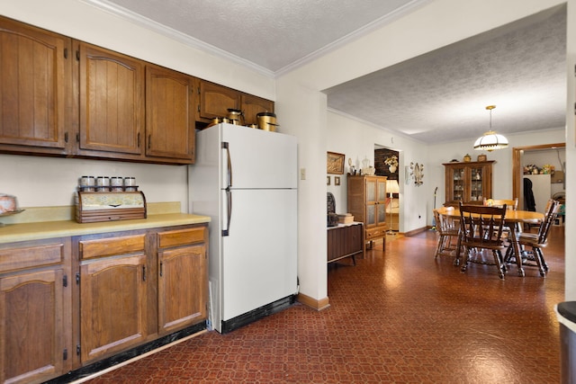 kitchen with crown molding, white refrigerator, hanging light fixtures, and a textured ceiling