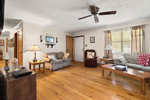 living room featuring ceiling fan, a textured ceiling, light wood-type flooring, and ornamental molding