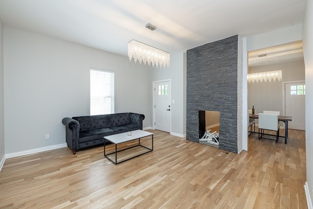 living area with plenty of natural light, baseboards, light wood finished floors, and a chandelier