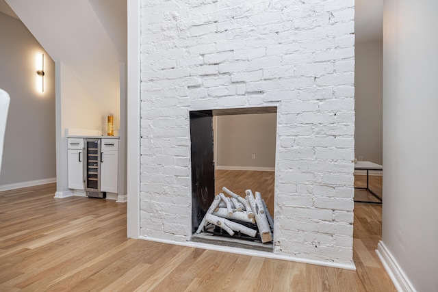 details featuring a dry bar, wine cooler, baseboards, and wood finished floors