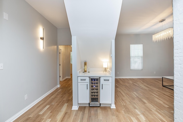 kitchen with light countertops, wine cooler, light wood-type flooring, and baseboards