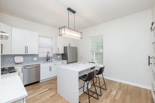 kitchen featuring a breakfast bar, stainless steel appliances, tasteful backsplash, light countertops, and a kitchen island