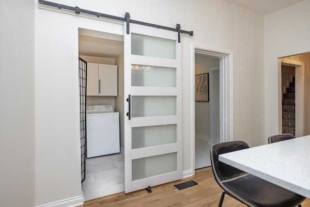 dining area with a barn door, visible vents, washer / clothes dryer, and light wood-style floors