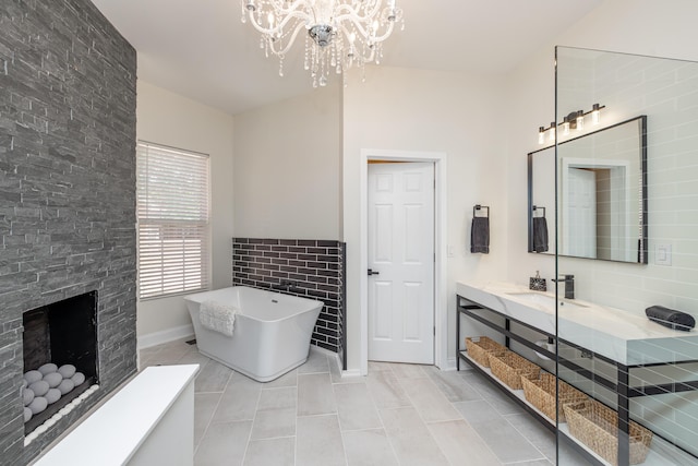 full bath with a fireplace with raised hearth, tile patterned flooring, a notable chandelier, vanity, and a freestanding bath