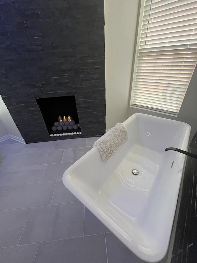 bathroom with a warm lit fireplace and tile patterned flooring