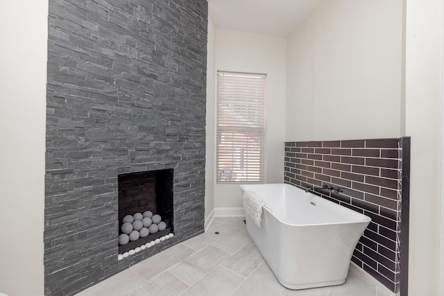 bathroom with a soaking tub, a fireplace, and tile patterned floors