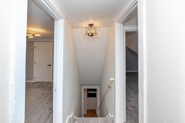 stairway with baseboards, an inviting chandelier, wood finished floors, and a textured wall