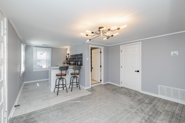 kitchen featuring ornamental molding, a breakfast bar, visible vents, and baseboards