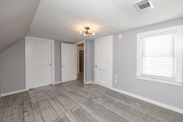 additional living space with visible vents, carpet flooring, lofted ceiling, and baseboards