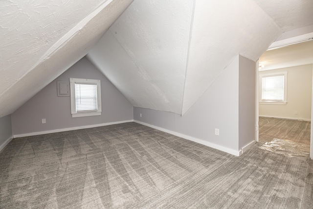 bonus room with lofted ceiling, carpet flooring, baseboards, and a textured ceiling