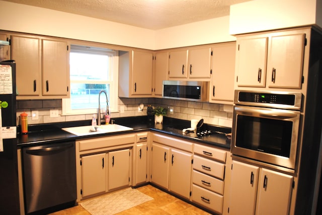 kitchen with appliances with stainless steel finishes, a textured ceiling, tasteful backsplash, and sink