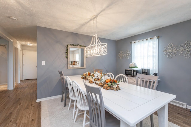 dining space with a textured ceiling and hardwood / wood-style floors