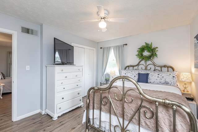 bedroom with ceiling fan, hardwood / wood-style flooring, a closet, and a textured ceiling