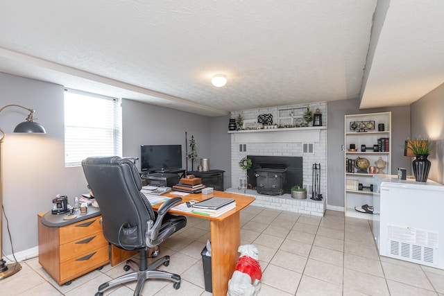 office with a textured ceiling, a fireplace, light tile patterned floors, and a wood stove