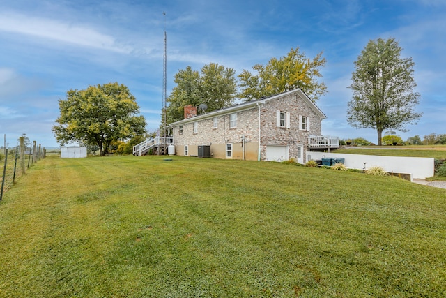 back of property with a yard, a garage, and central AC unit