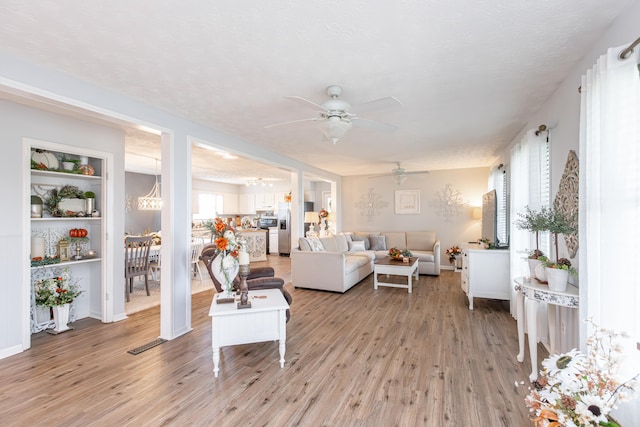 living room featuring light hardwood / wood-style floors, plenty of natural light, ceiling fan, and a textured ceiling