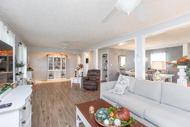 living room featuring a textured ceiling, ceiling fan, and light hardwood / wood-style flooring