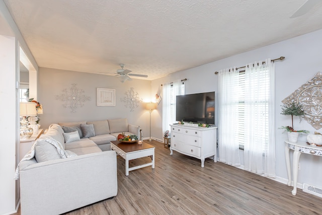 living room featuring ceiling fan, hardwood / wood-style flooring, and a textured ceiling