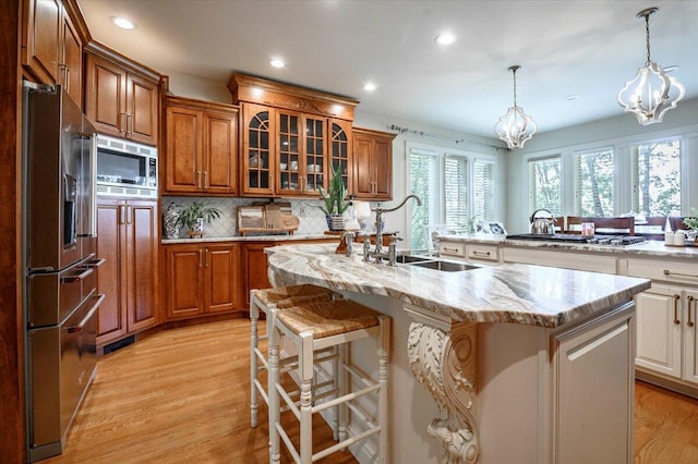 kitchen featuring a kitchen island with sink, sink, an inviting chandelier, a kitchen breakfast bar, and appliances with stainless steel finishes