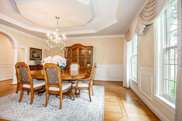 dining room with crown molding, a raised ceiling, a chandelier, and a wealth of natural light