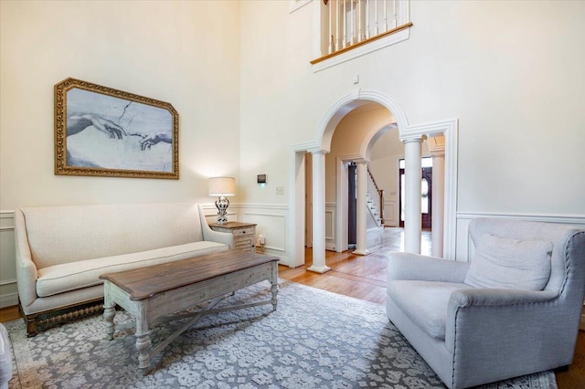 living room with a high ceiling, wood-type flooring, and decorative columns