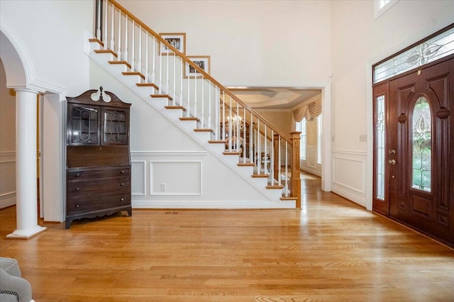 foyer featuring a high ceiling, decorative columns, and light hardwood / wood-style floors