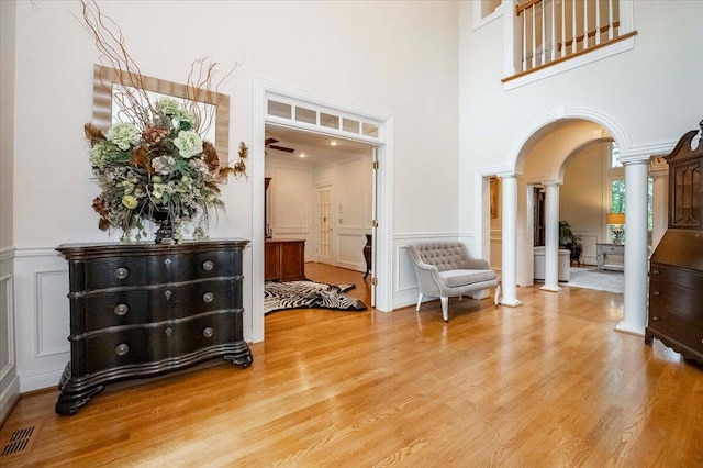 entryway featuring a high ceiling, wood-type flooring, and decorative columns