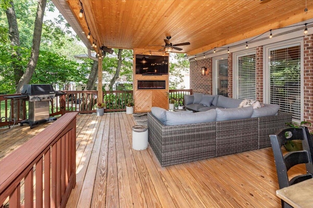 wooden deck with an outdoor hangout area, ceiling fan, and a grill