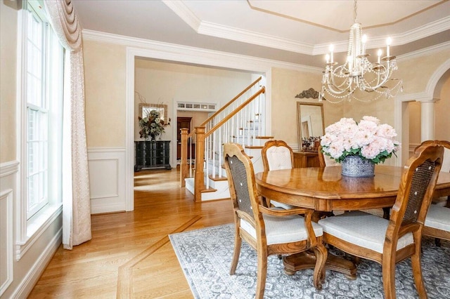 dining area with ornamental molding, wood-type flooring, and an inviting chandelier