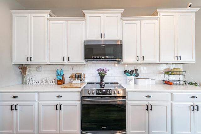 kitchen featuring decorative backsplash, stainless steel electric range oven, and white cabinets