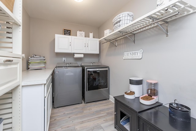 washroom featuring washer and clothes dryer, light hardwood / wood-style floors, and cabinets