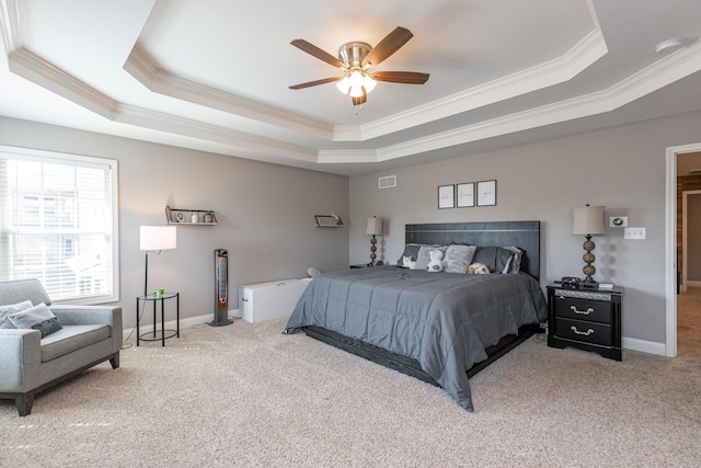 bedroom featuring ceiling fan, ornamental molding, light carpet, and a tray ceiling