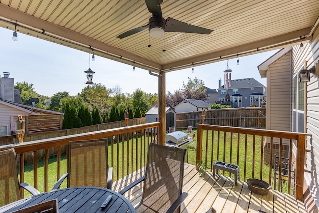 deck with area for grilling, ceiling fan, a yard, and a shed