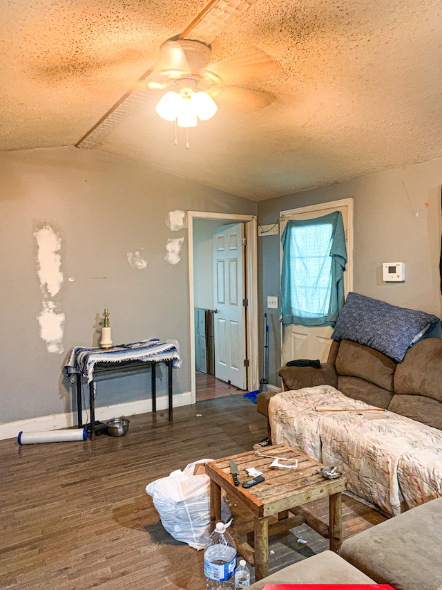 living room featuring ceiling fan, dark hardwood / wood-style floors, vaulted ceiling, and a textured ceiling