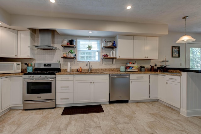 kitchen featuring wall chimney exhaust hood, white cabinetry, appliances with stainless steel finishes, and sink