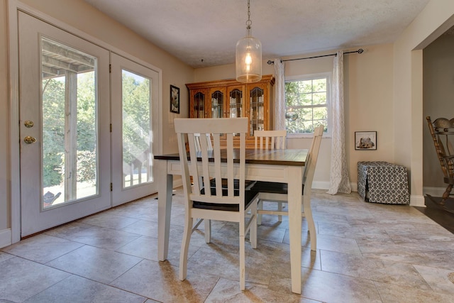 tiled dining space with a textured ceiling and a wealth of natural light