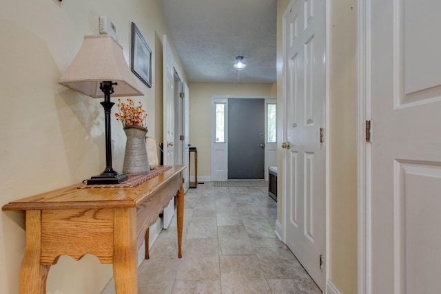 corridor featuring light tile patterned floors and a textured ceiling