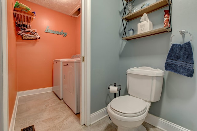 bathroom featuring toilet, a textured ceiling, and washer and dryer