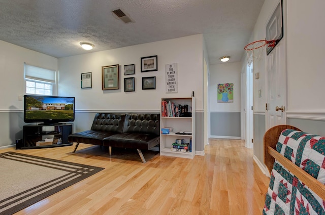 living room with light wood-type flooring and a textured ceiling