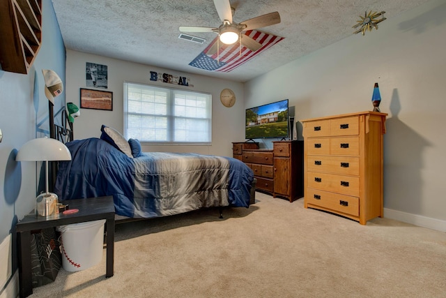 carpeted bedroom featuring ceiling fan and a textured ceiling