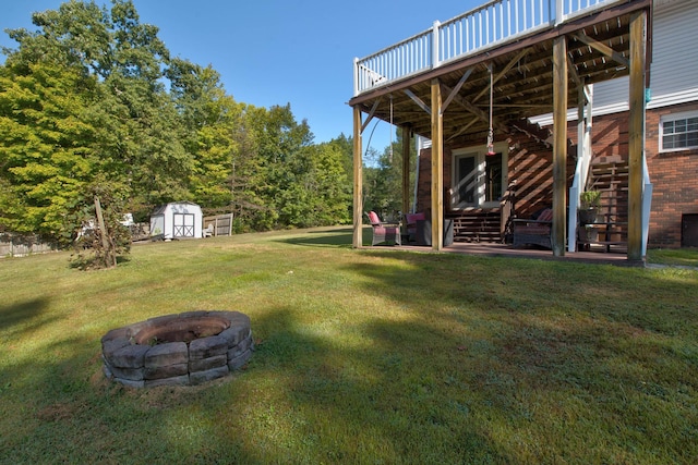 view of yard featuring an outdoor fire pit, a wooden deck, and a storage unit