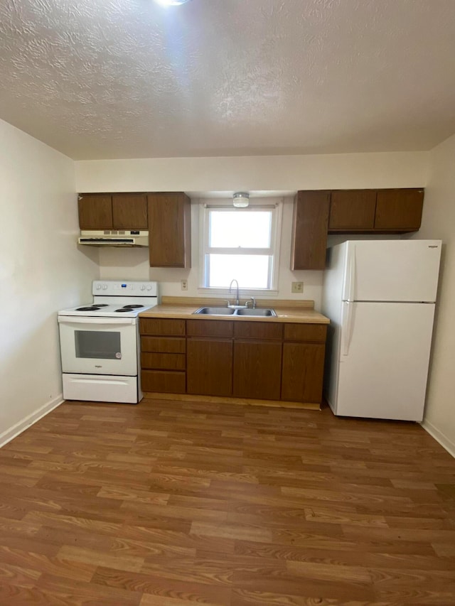 kitchen with white appliances, a textured ceiling, dark wood-type flooring, and sink