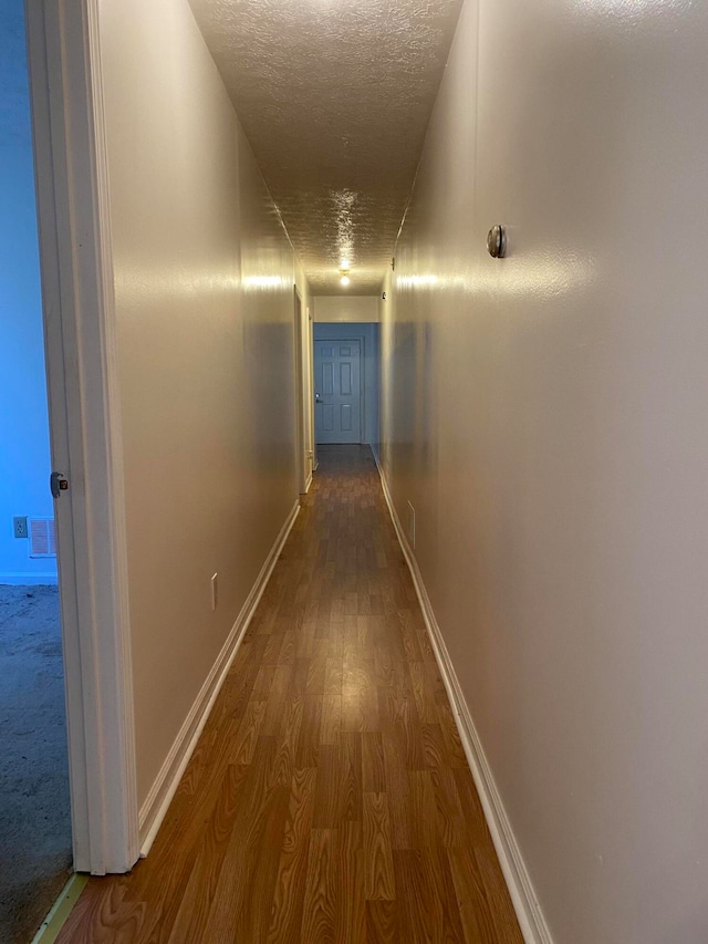 hallway featuring a textured ceiling and wood-type flooring