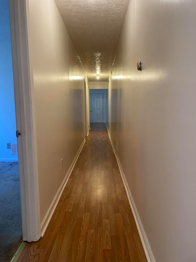 hallway featuring hardwood / wood-style floors and a textured ceiling