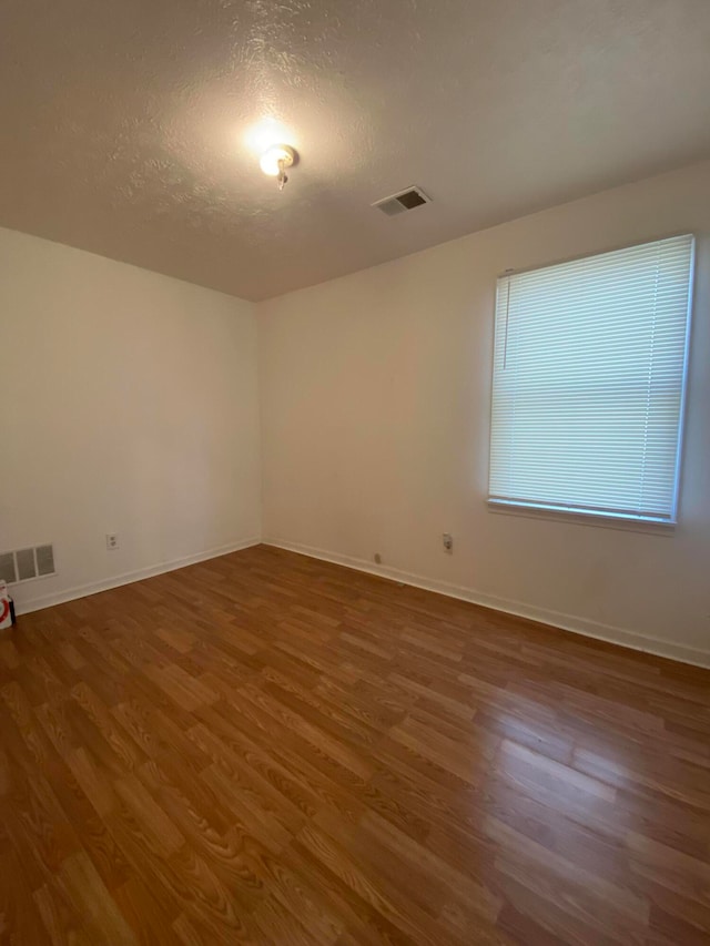 spare room featuring wood-type flooring and a textured ceiling