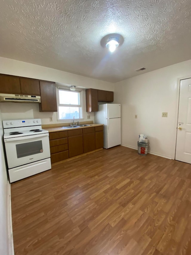 kitchen featuring white appliances, a textured ceiling, wood-type flooring, and sink