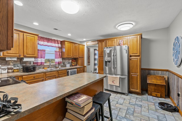 kitchen with a breakfast bar, a textured ceiling, tasteful backsplash, sink, and appliances with stainless steel finishes