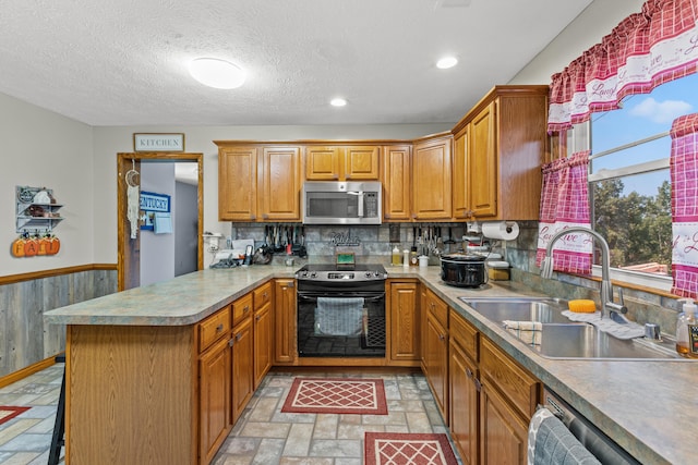 kitchen with sink, kitchen peninsula, a textured ceiling, stainless steel appliances, and a kitchen bar